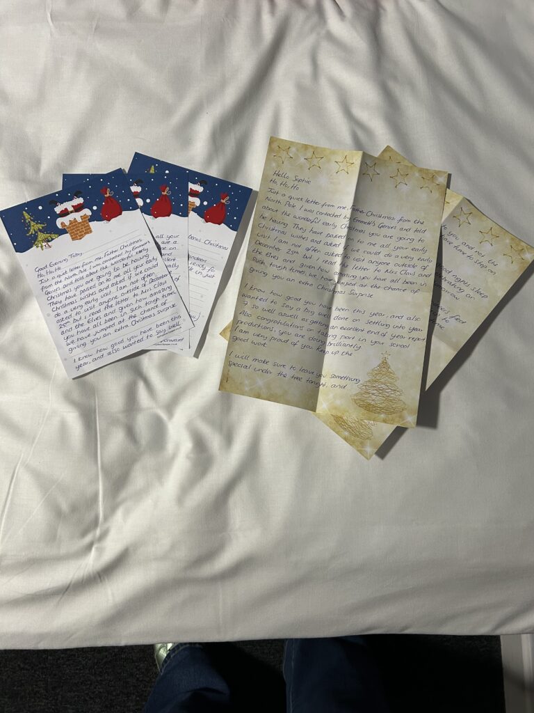 Three handwritten letters on festive stationery are spread out on a white surface. Two feature Emmett's Genies, with Christmas stockings and trees, while one is yellow with stars and a charming Christmas tree illustration.