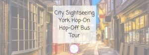 The Shambles in York. A narrow, empty street with old buildings on both sides. Text in the centre reads, City Sightseeing York Hop-On Hop-Off Bus Tour. Background has a faded, vintage look.