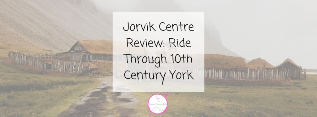 Viking-style wooden houses with thatched roofs and a wooden fence, set against foggy hills, evoke the atmosphere of Jorvik. Text overlay reads: Jorvik Centre Review: Ride Through 10th Century York.